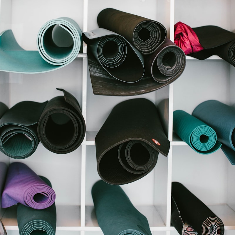 Colorful rolled yoga mats organized in white cubby shelves at a studio